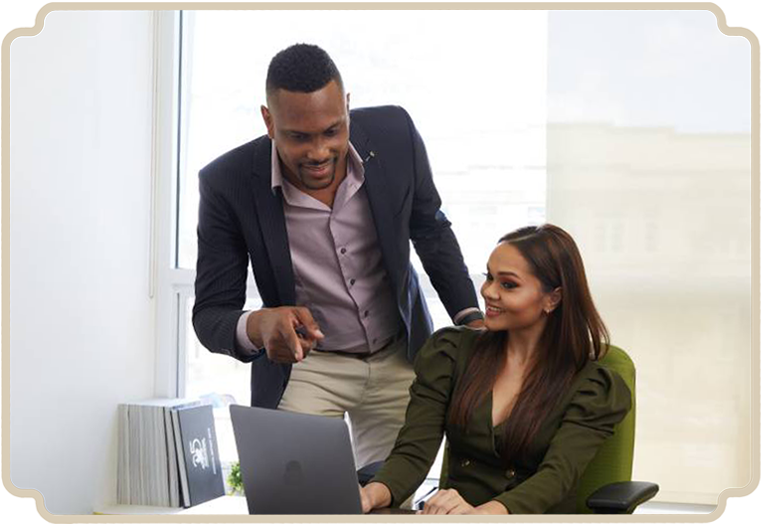 Public servant, possibly a lawyer, engaged in a discussion with a First Citizens bank employee about a loan, both reviewing financial details on a laptop.